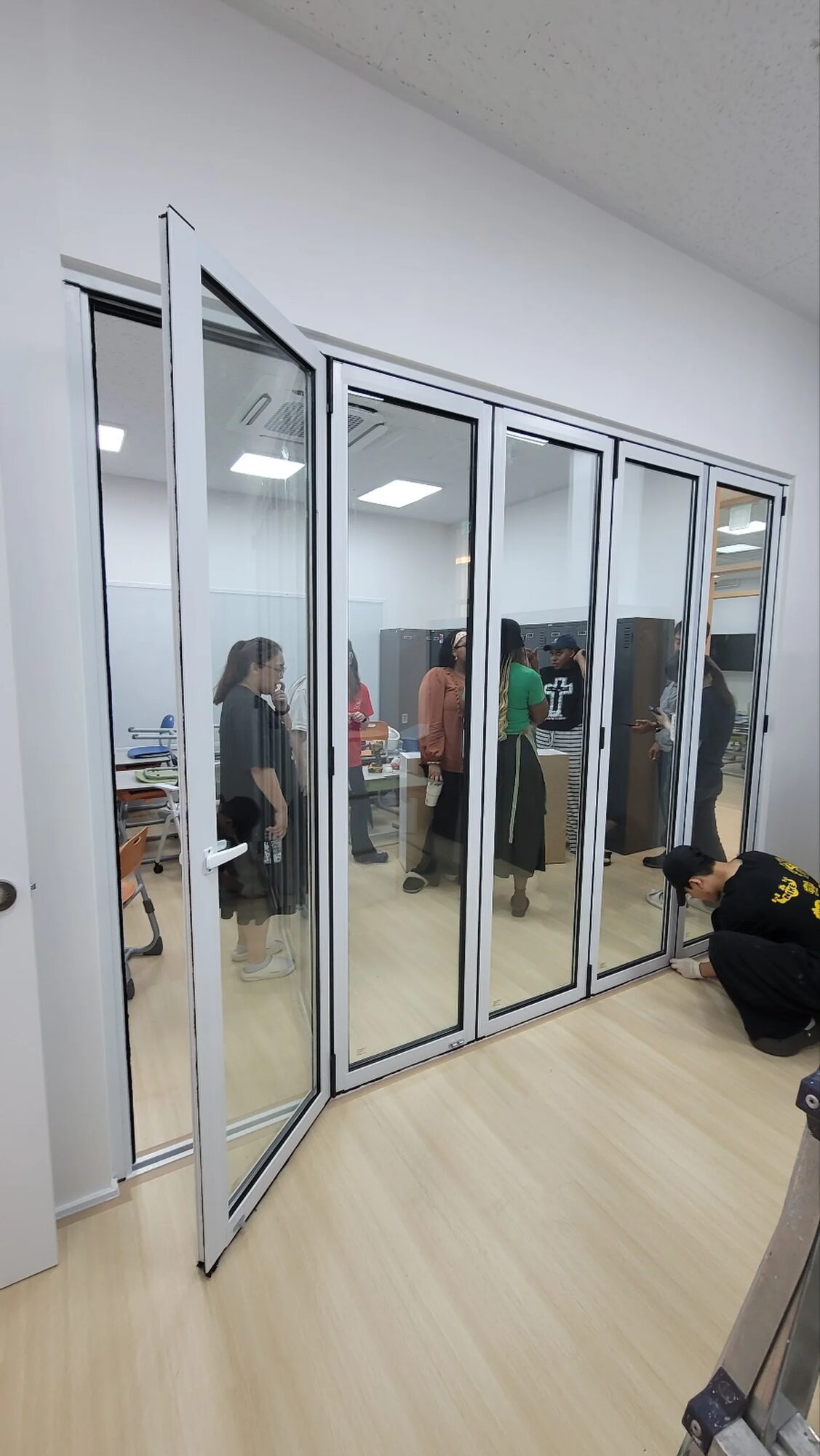 교육시설 강의실 개구부에 시공 중인 흰색 프레임 폴딩도어